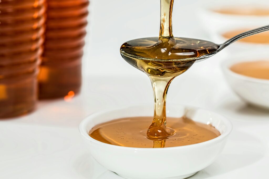 Honey dripping on to a spoon, spilling over in to a white bowl