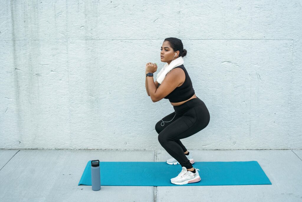 A woman wearing headphones and gym gear doing a squat workout