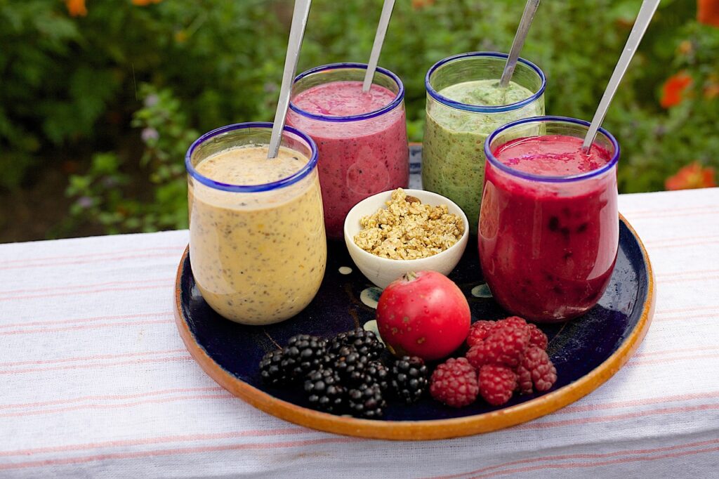 An assortment of smoothies on a tray, surrounded by fresh fruit.