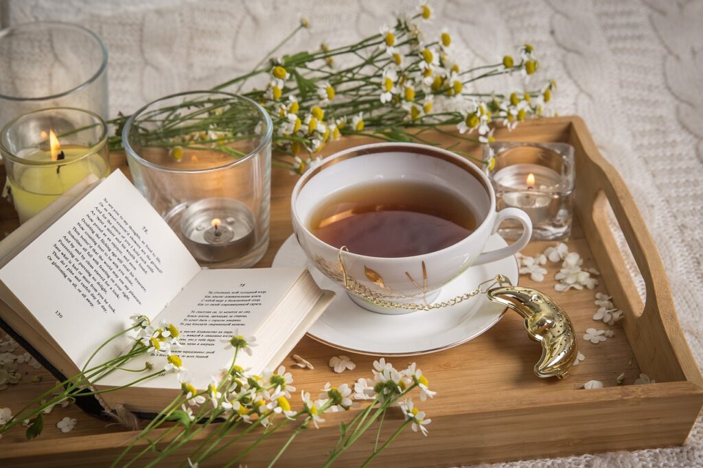 A cup of chamomile tea, surrounded by chamomile flowers on a wooden table