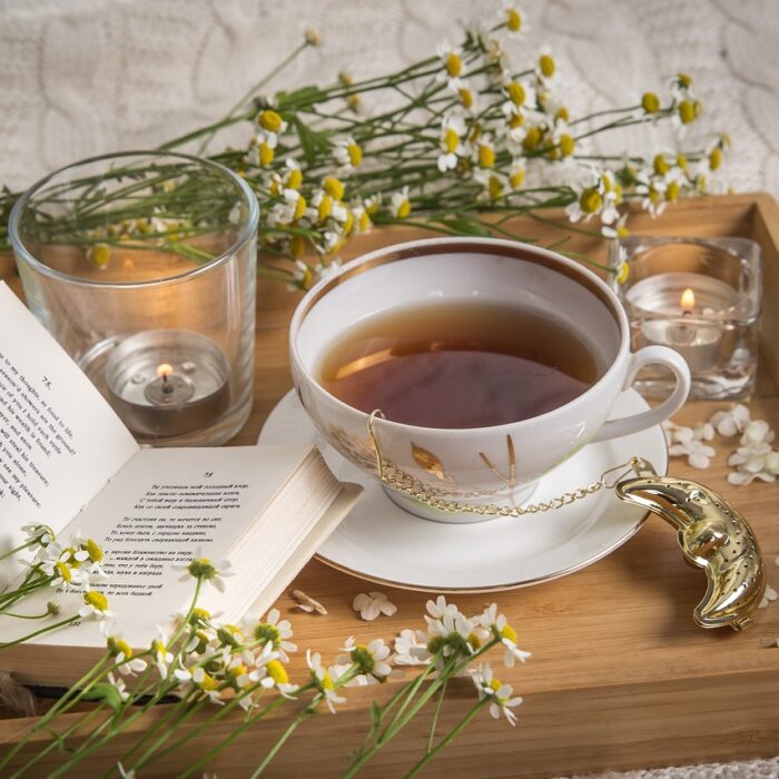 A cup of chamomile tea, surrounded by chamomile flowers on a wooden table