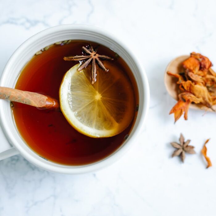 A bird's-eye view of a cup of cinnamon tea with a slice of lemon floating inside.