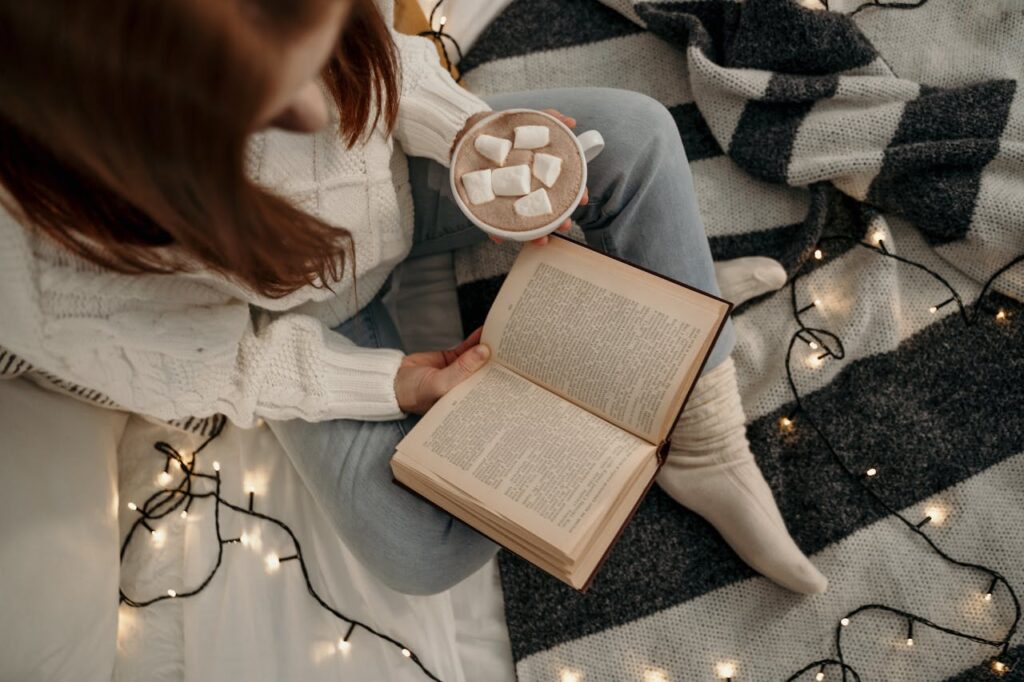 A bird's-eye view of a woman reading a book and enjoying her hot chocolate