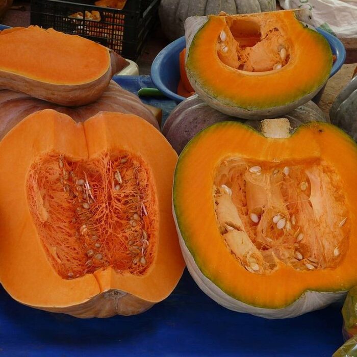 Two halves of a pumpkin showing the inside with seeds visible.