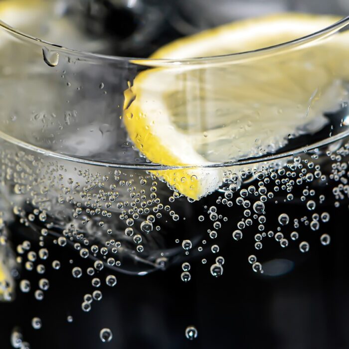 Two fresh lemon slices floating in a crystal-clear glass of water, catching the light with a vibrant, refreshing glow