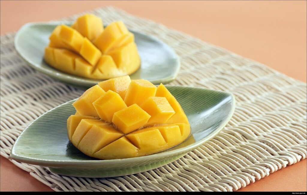 A mango cut in half on each plate, with the flesh cubed but left intact inside the fruit.