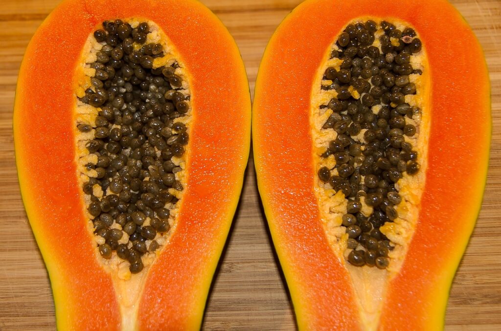 A papaya sliced in half, placed on a wooden table